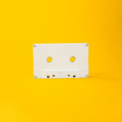 Old white music cassette on a yellow background. Music. Retro.