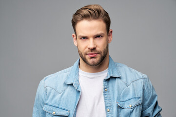 Fototapeta premium Portrait of young handsome caucasian man in jeans shirt over light background