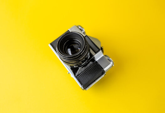 Old analog camera on a yellow background. Analog photography. Copy Space.