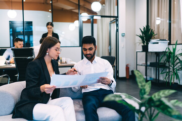 Serious young multiracial businesspeople analyzing reports in workspace