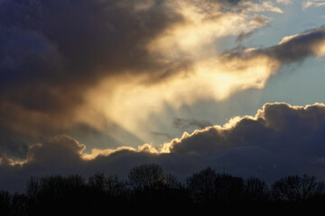 Thick clouds obscure the sun but the rays are breaking through