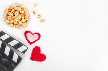 Valentine's Day movie concept. Clapperboard with hearts and caramel popcorn with copy space