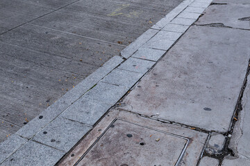 Urban background of finely grooved concrete road and grey stone curb, cracked sidewalk, horizontal aspect