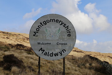  A faded, bilingual welcome sign for the old Welsh county of Montgomeryshire, UK.