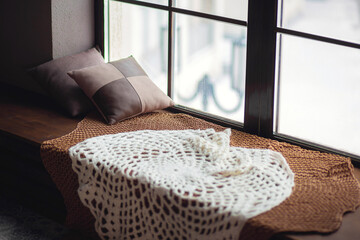 Fototapeta na wymiar Winter window. Warm knitted bedspread on the windowsill with pillows