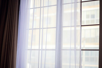 Large panoramic windows covered with white tulle