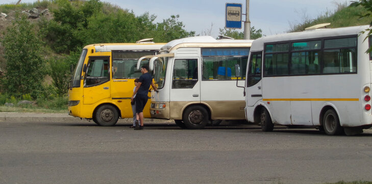Kazakhstan, Ust-Kamenogorsk, may 21, 2020: Three chinese buses at the bus stop. Terminal bus stop. Public transport. Commercial vehicles. City buses. Man and Woman