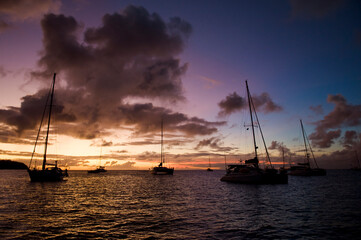 Anchoring ships in tropical bay at sunset. Small yachts and catamarans on sea water during dusk. Santa Lucia. Caribbean lifestyle themes