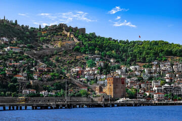 Fototapeta na wymiar Seascape with Red Tower and Alanya Castle on top of a hill (Turkey). Beautiful landscape with the landmarks of the Turkish resort