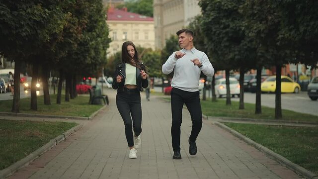 A man and a woman are walking around the city. They are smiling and jumping. 4K.