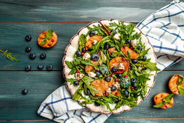 Easy recipe for summer salad with goat cheese, grilled apricots, arugula, berries, close-up on a...