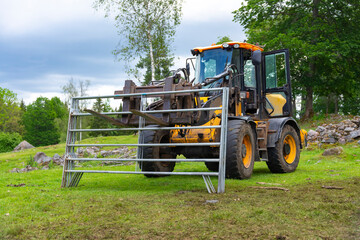 Yellow tractor mowing the fence in forest farm in Sweden, fence building, farm work, machinery, modern farming