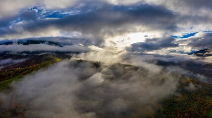 Flight through blue sky with clouds over mountain