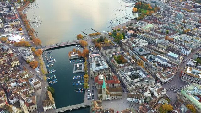 Aerial footage with backward motion of the Zurich old town along the Limmat river with the medieval cathedral and buildings contrastic with the modern and financial business district on the right