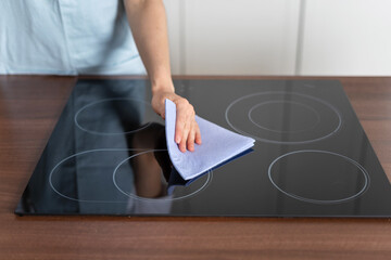 Woman cleaning electric stove with ceramic surface