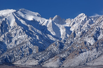 Winter landscape of the Eastern Sierra Nevada Mountains covered in snow and framed by a clear blue sky, near Lone Pine, California, USA