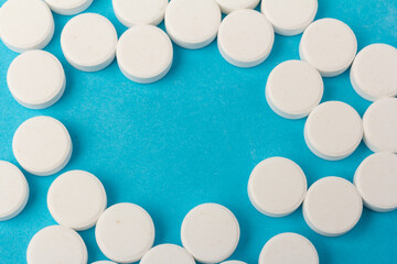 Heap of pills on blue background. Medicine, pharmacy and health concept.