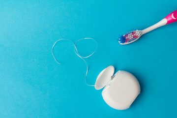 Dental floss and toothbrush on blue background.Personal dental hygiene accessories.