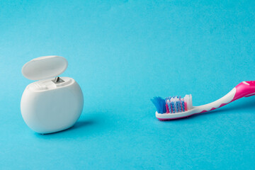 Dental floss and toothbrush on blue background.Personal dental hygiene accessories.