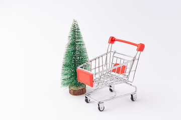 mini supermarket trolley on a white background, next to a small Christmas tree, isolate, used as a background or texture