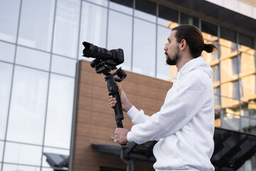Young Professional videographer holding professional camera on 3-axis gimbal stabilizer. Pro...