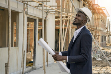 Black man races in a suit is an executive, a construction engineer, inspects the construction of a house, has scaffolding on the construction site of the Real Estate project.