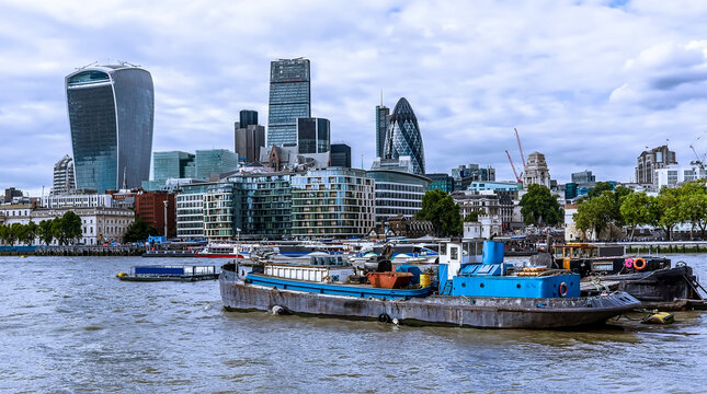 Old and new aspects of London with Thames barges in the foreground and the City of London in the background viewed from the banks of the River Thames, London, UK