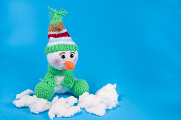 Toy knitted snowman in cap and scarf on blur background.  Copyspace for text