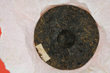 Disc of Chinese puer tea isolated on a white wrapping paper. Minimalism. Copy space. 
