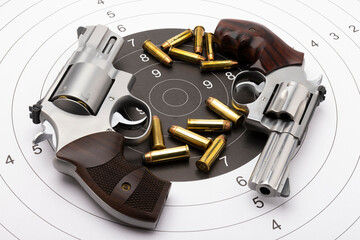 Revolver hand gun pistols and bullets on bull eye target background