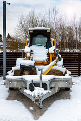 Сonstruction equipment on a trailer. Mini excavator in the area under the surveillance camera.