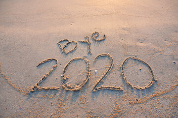 Goodbye 2020 inscription written on the sandy beach. New year conceptual.