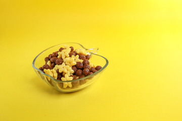 A bowl of chocolate and corn cereal isolated on the yellow background 