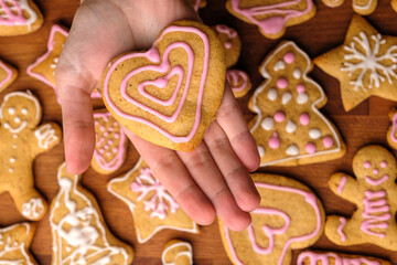 Fototapeta na wymiar Cookies for Valentines Day in woman hands in the background of gingerbread. 