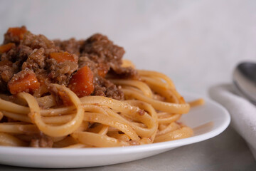 White Plate of Pasta alla Bolognese with Meat Sauce, Cheese and Vegetables