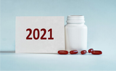 On a light blue background a card with the text 2021 near the white bottle pills.