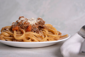 White Plate of Pasta alla Bolognese with Meat Sauce, Cheese and Vegetables