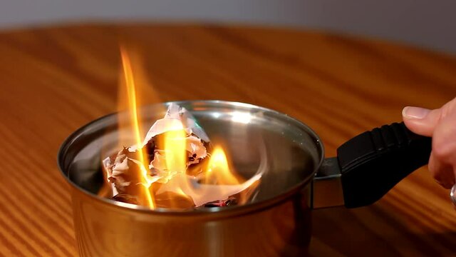 Papers burning into small casserole pot. Memories removal, promise commitment, getting rid of evidence, letters, documents elimination concepts