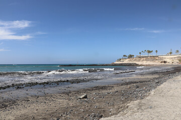 Waves crashing over the black sand and rocks on a beach in Tenerife
