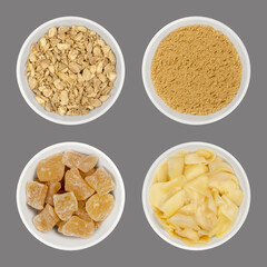Processed ginger root in white bowls, over gray. Dried and ground, candied ginger cubes and pickled slices. Zingiber officinale. Used as spice, tea, snack and for sushi. Food photo closeup from above.
