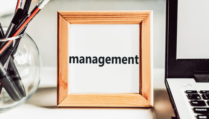 MANAGEMENT. Text in wooden frame on office table.