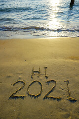 Hi! 2021 inscription written on the sandy beach. Happy new year concept.