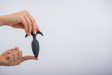 Faceless woman holding a black anal plug on a white background. Assortment of sex shop