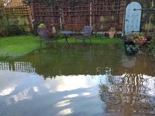 Landscape of flooded garden after heavy rain storms with sky and cloud reflected in the pool of...