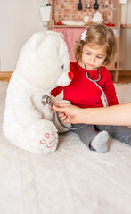 Portrait of cute adorable baby girl playing doctor or nurse with stethoscope at home or kindergarten. Funny child and role playing.