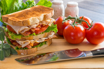 Fresh turkey club sandwich on a cutting board with ingredients