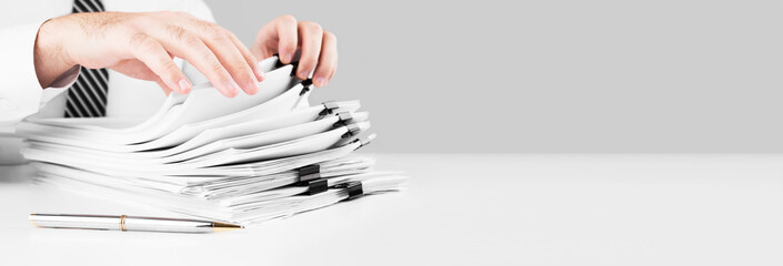 Businessman hands working in stacks of paper files for searching information, business and financial concept.