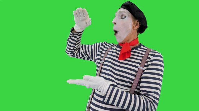 Male mime artist performing showing growth, high interest rates, high income with his hands on a Green Screen, Chroma Key.