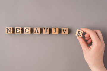 Pessimism concept. Close up top view photo of female hand putting wooden cubes with negative word...