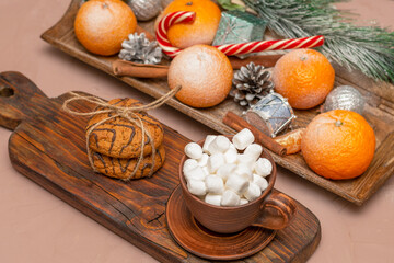 Coffee or cocoa with marshmallows on a long vintage board in a Christmas composition. Oatmeal cookies and tangerines with sweets on the festive table. Selective focus